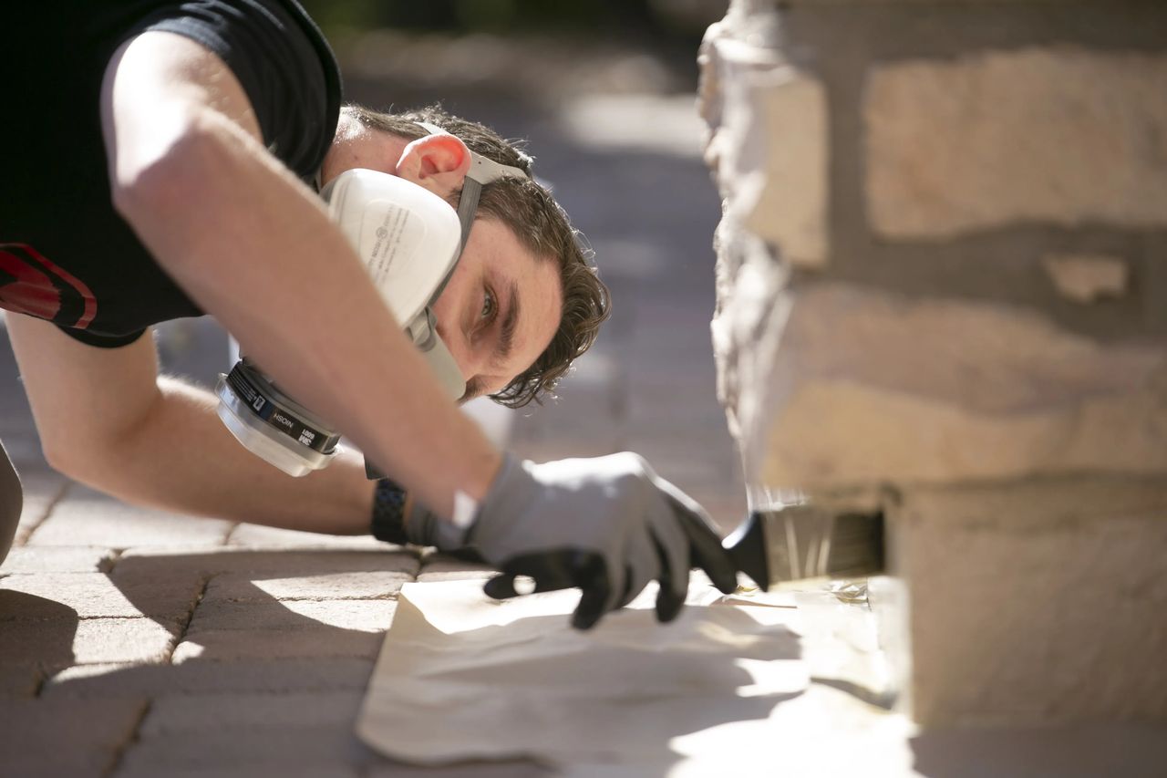 Technician applying Slick Barrier at a home's foundation